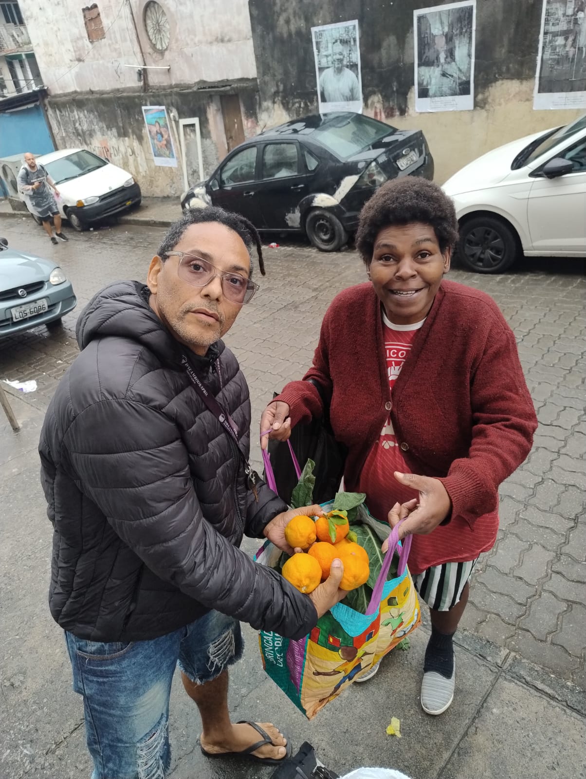 Evandro entregando sacola de frutas a moradora